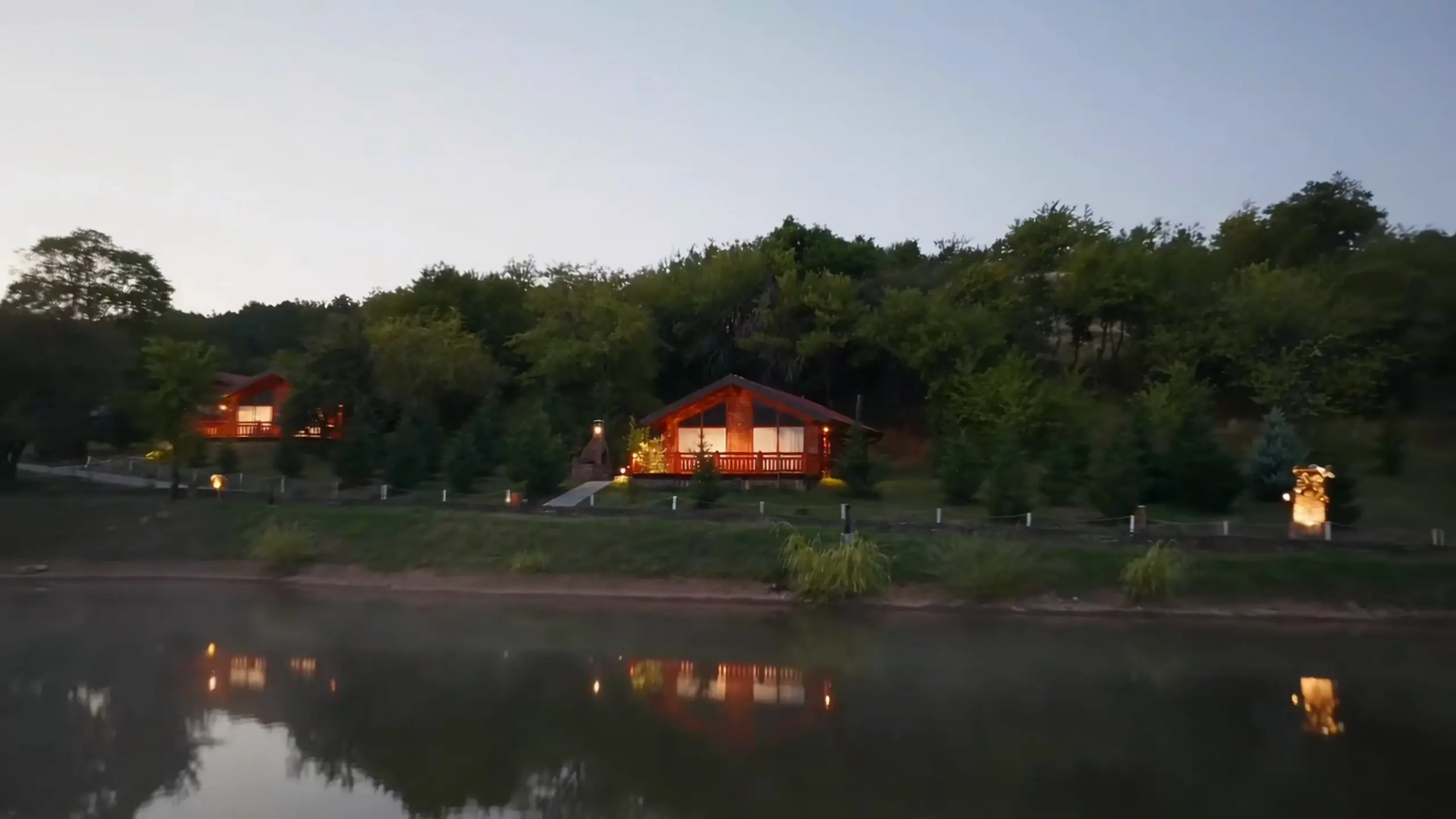 The timber villas of BioLand on the hillside above the lake